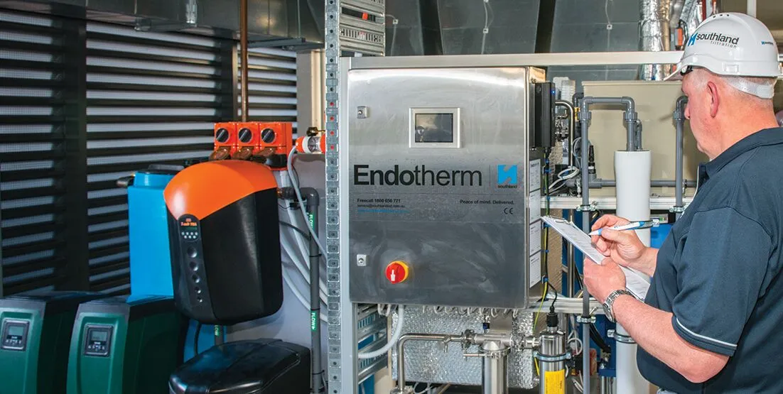 Person wearing white hard hat, with a clipboard looking at Reverse Osmosis system