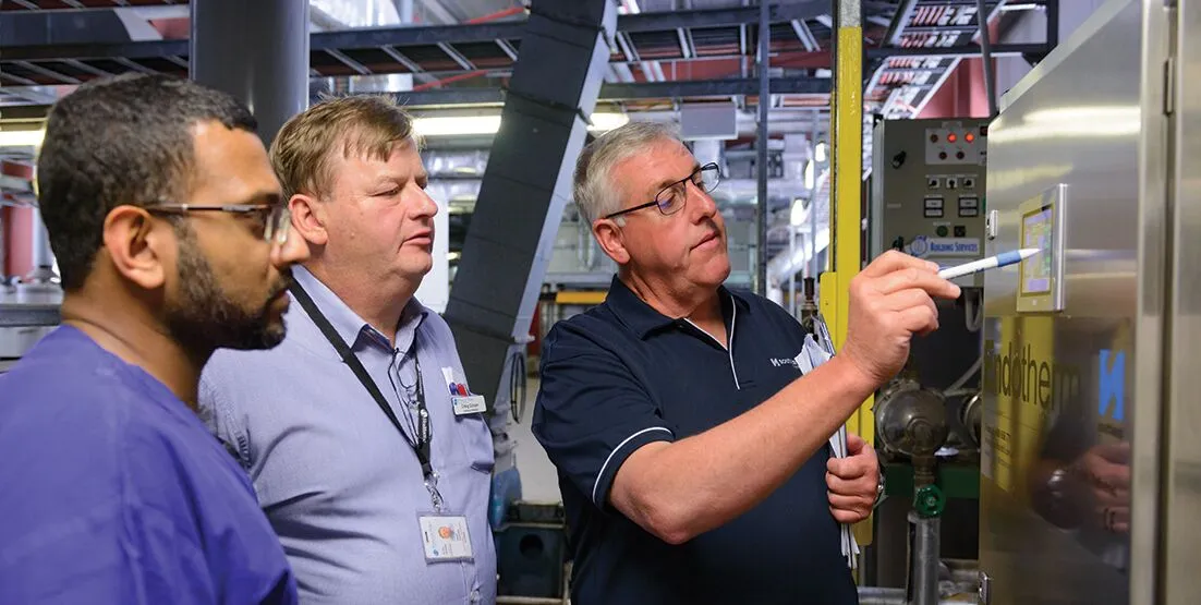 photo of three people looking at the control panel of a Reverse Osmosis system.