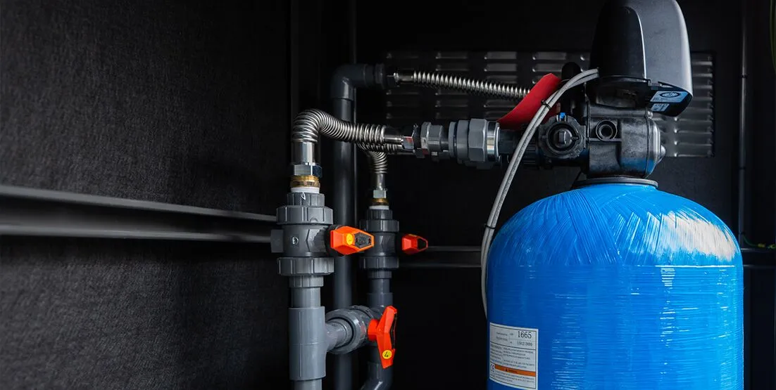 A close up profile photo of a tank as part of a water filtration system along a black wall